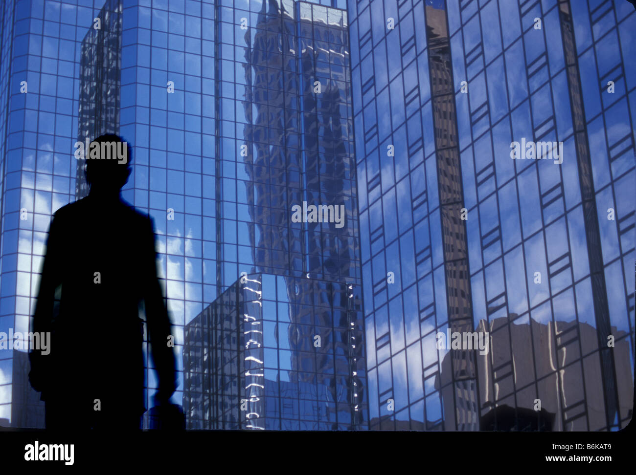 Geschäftsmann mit Aktenkoffer zu Fuß unter hohen modernen Bürogebäuden Stockfoto