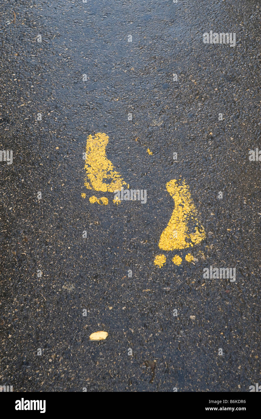 Fußabdrücke in gelber Farbe auf einer asphaltierten Straße Stockfoto