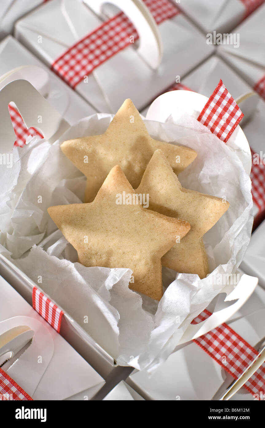 Sterne geformten Ausschnitt Kekse in einfache schlichte weiße Boxen für verpackt präsentiert zu Weihnachten. Gefesselt mit rot karierte Schleife Stockfoto