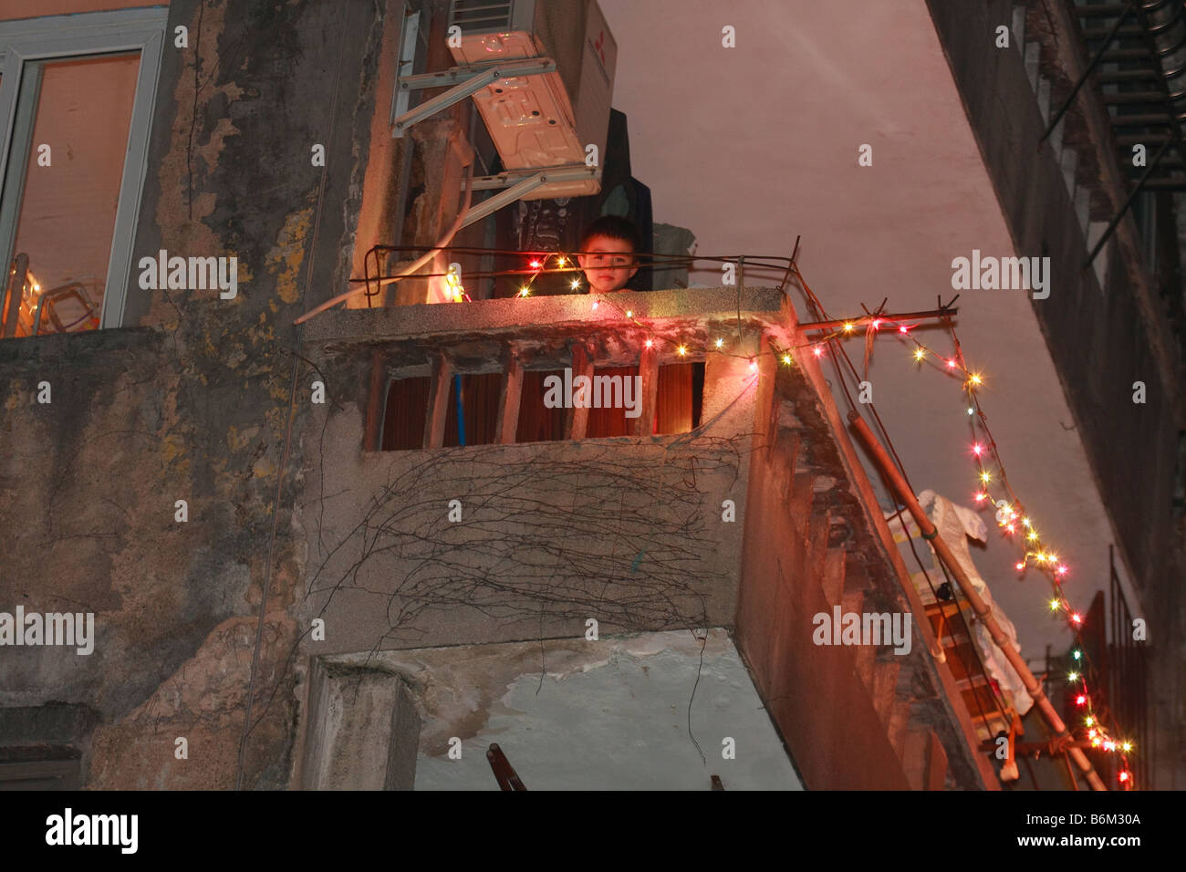 Asiatische junge Kollegen vom Balkon im Haus in China durch Drähte über Weihnachtsbeleuchtung während der konjunkturellen Abschwächung globaler Krisen Stockfoto