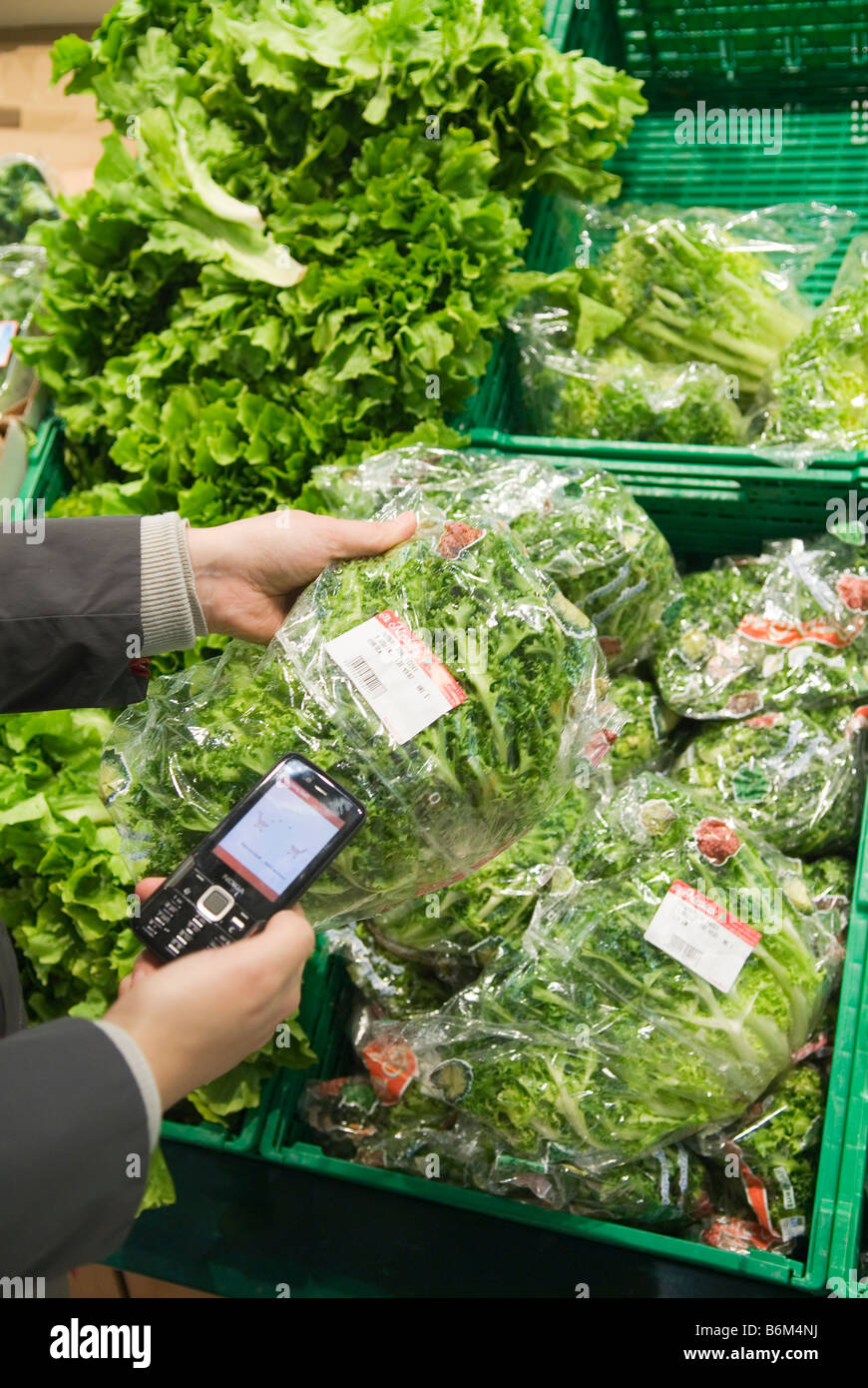 junge Frau scannt den Preis für ein verpackter Salat in ihr Handy im real Future Store Teil der Metro Group Stockfoto