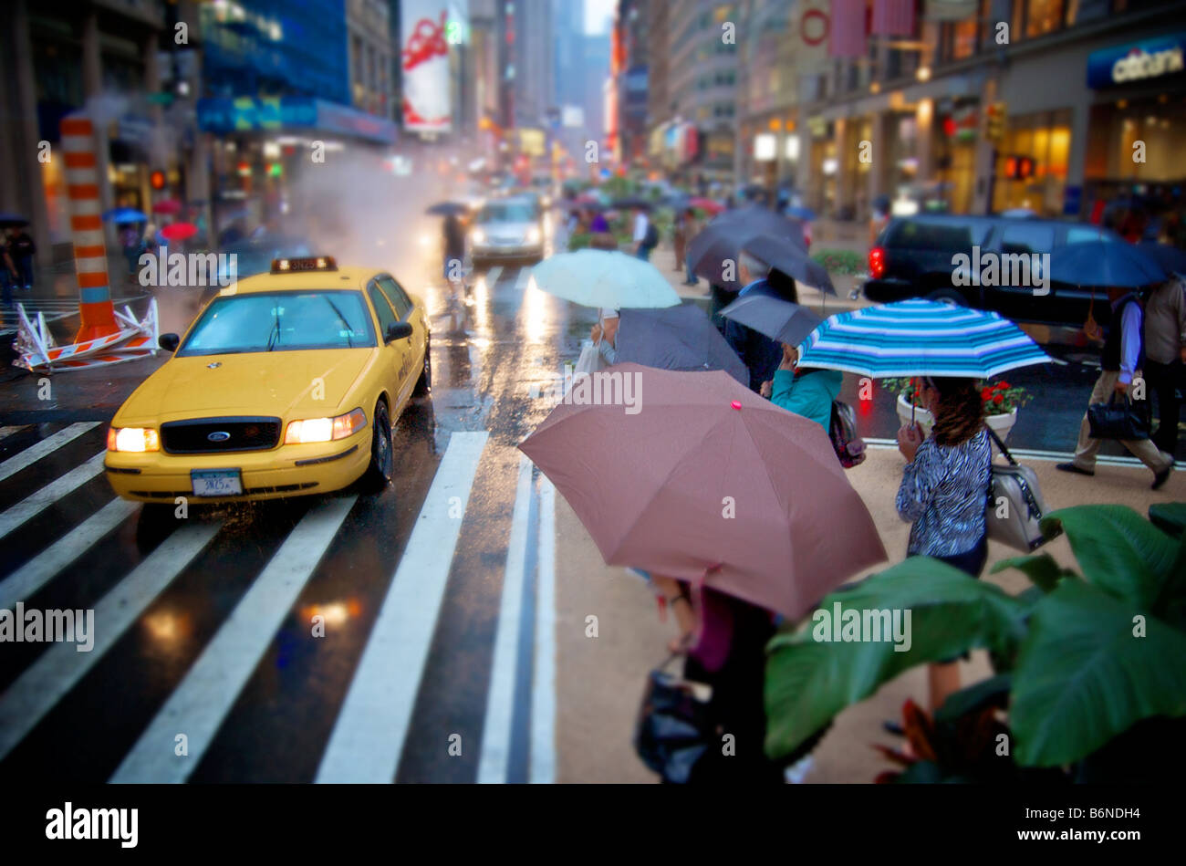 Es regnet Straßenszene, Menschen mit Sonnenschirmen und Verkehr in New York City USA Stockfoto