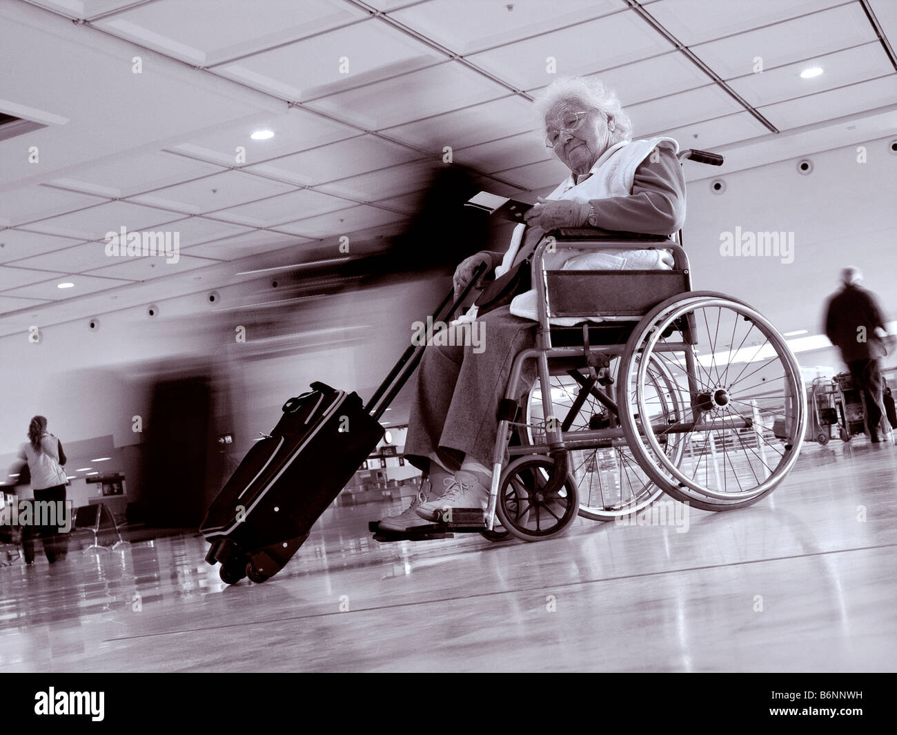 Unabhängige Seniorin im Rollstuhl wartet auf geschäftigen Flughafen Halle ihre Tickets für die Reise vorbereiten Stockfoto