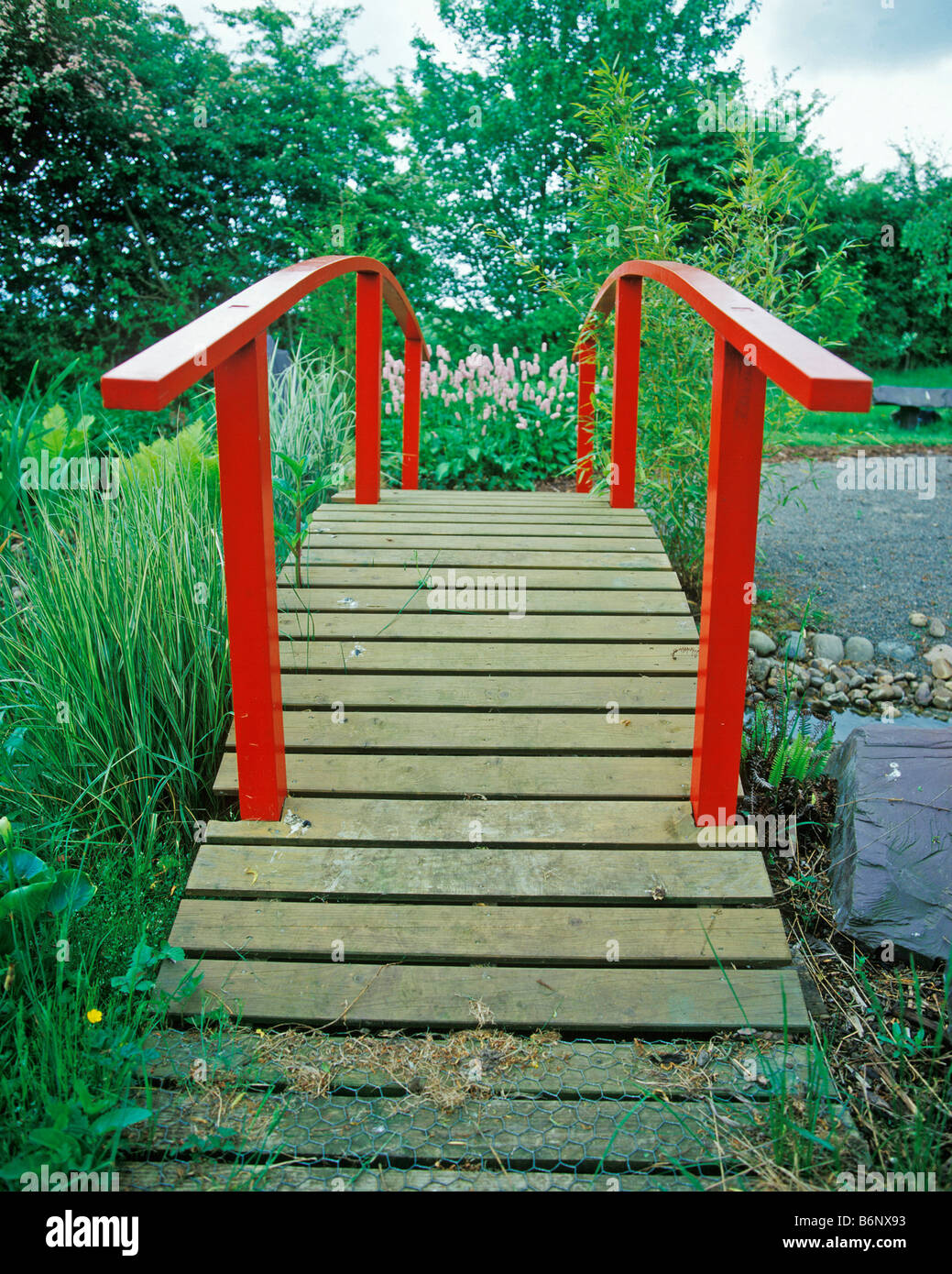 ROTEN HÖLZERNEN JAPANISCHEN BRÜCKE SPANNING GARTEN STREAM Stockfoto