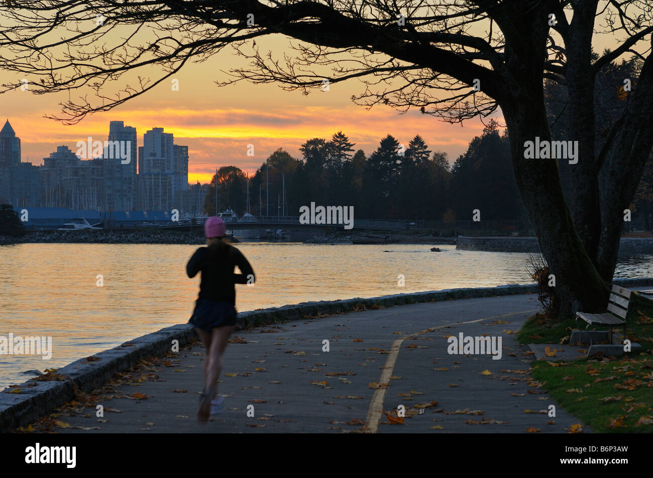 Weibliche Jogger auf der Ufermauer im Stanley Park Vancouver nach Sonnenuntergang Stockfoto