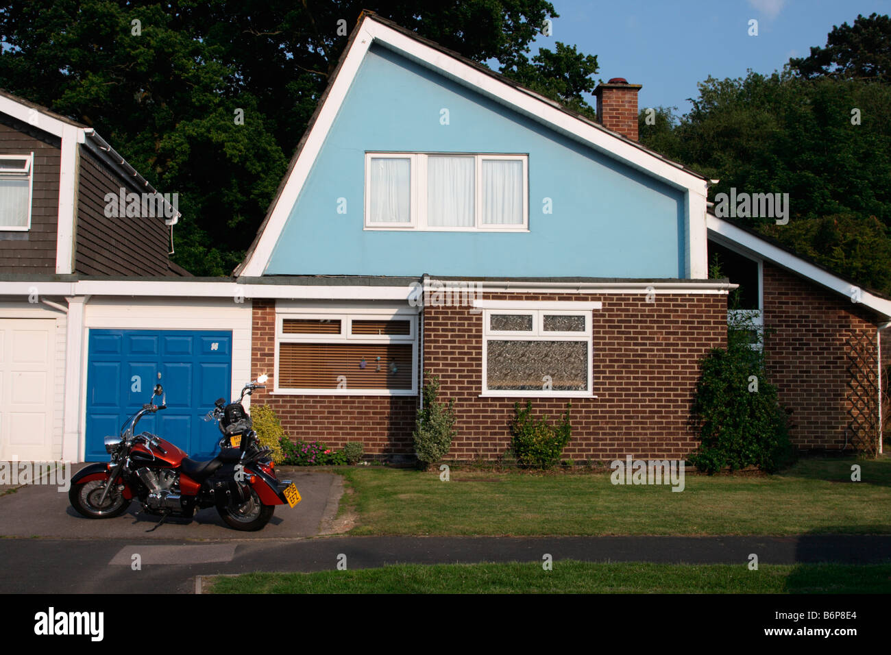 1960er Jahren Vorstadthaus Waterlooville, Portsmouth Hampshire UK mit großen roten Motorrad vor Garage in Fahrt. Stockfoto