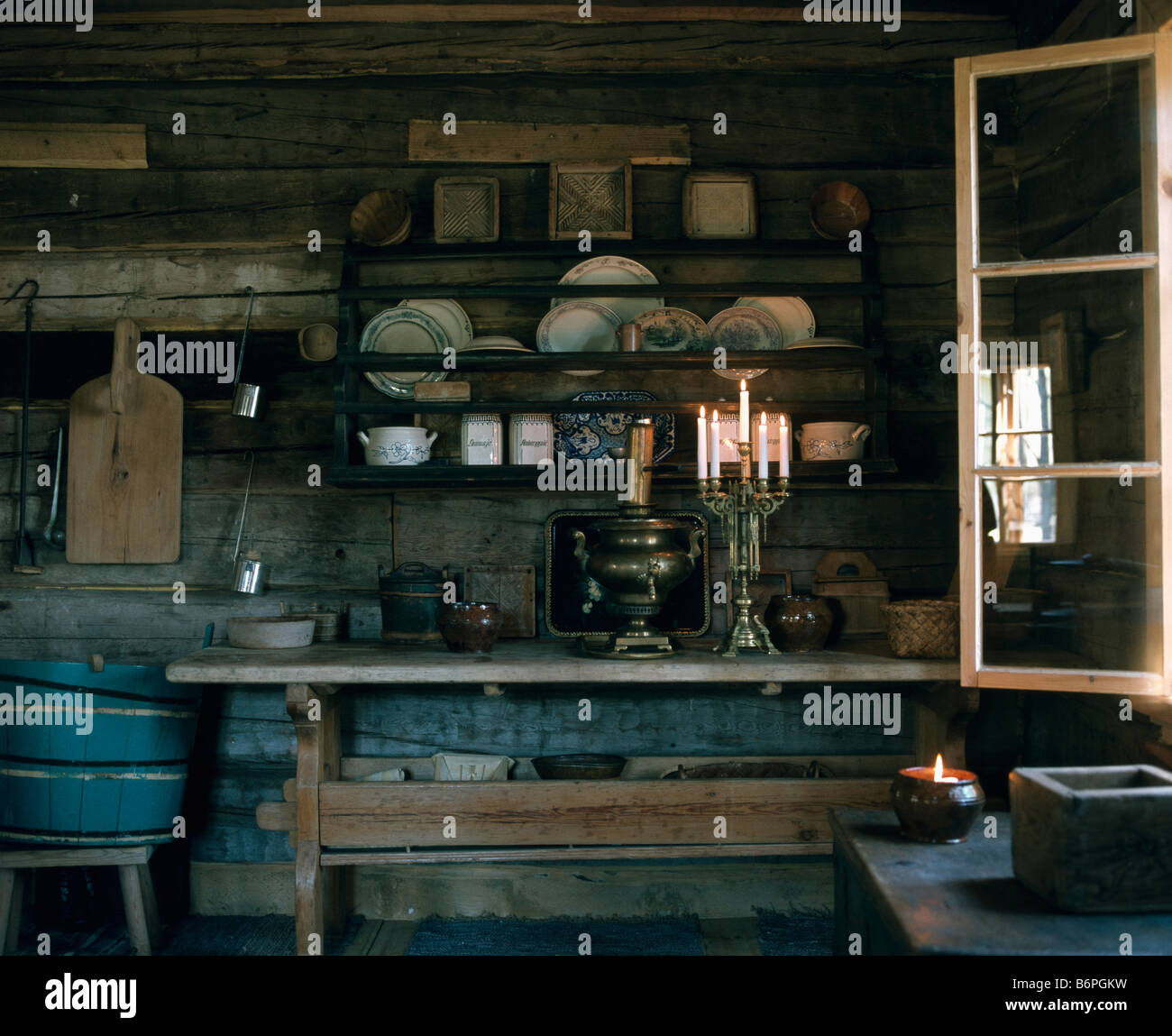 Kandelaber mit brennenden Kerzen am Tisch vor alten hölzernen Tellerhalter in rustikale französische Küche Stockfoto