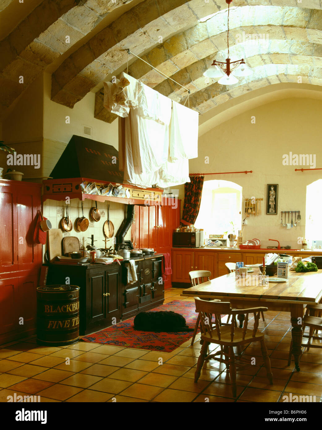 Blätter trocknen auf lüften Rack über schwarze Aga-Ofen im großen Keller Küche mit Holztisch und gewölbte Decke Stockfoto