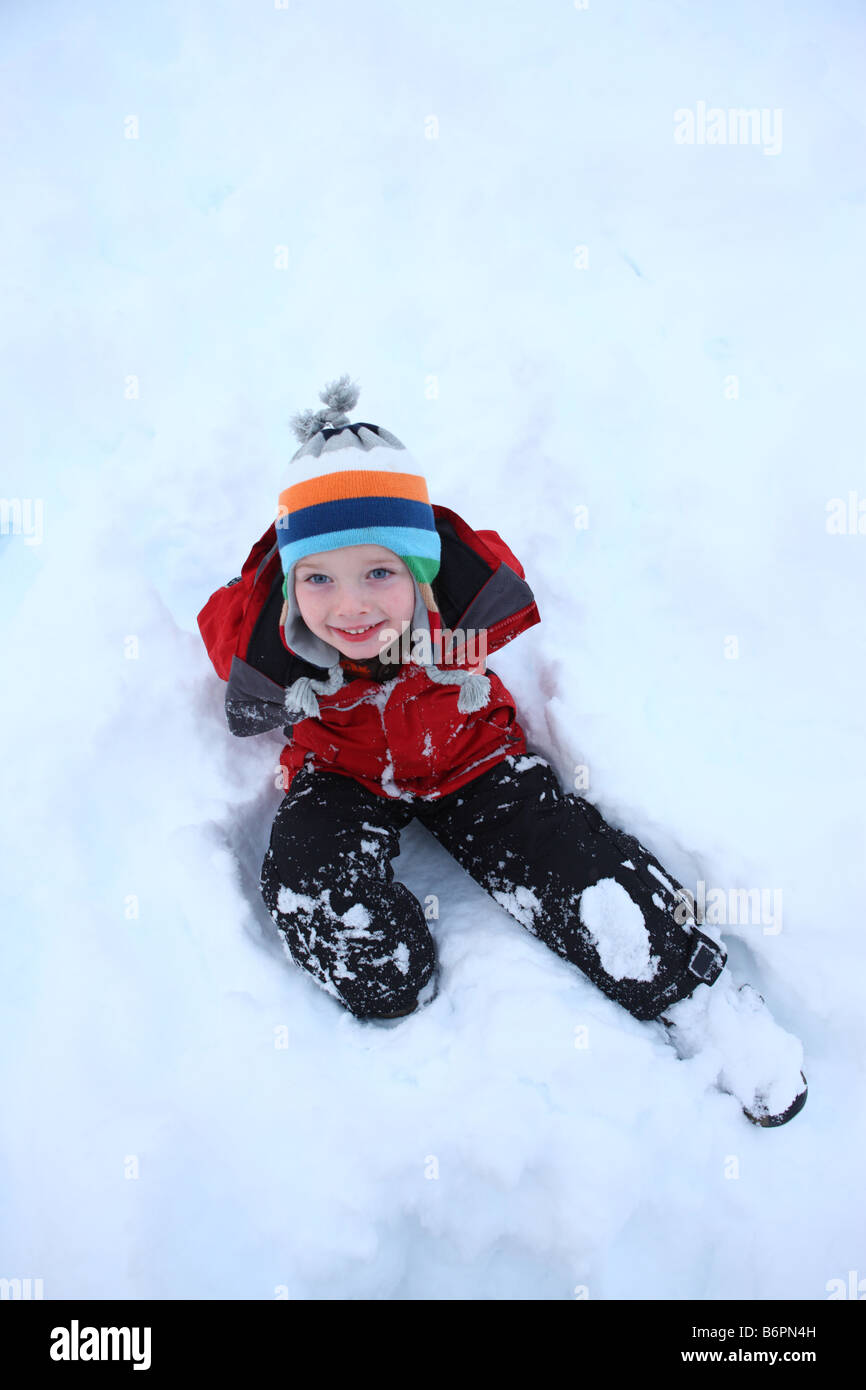 Kleiner Junge sitzen im Schnee nach oben auf der Kamera Stockfoto