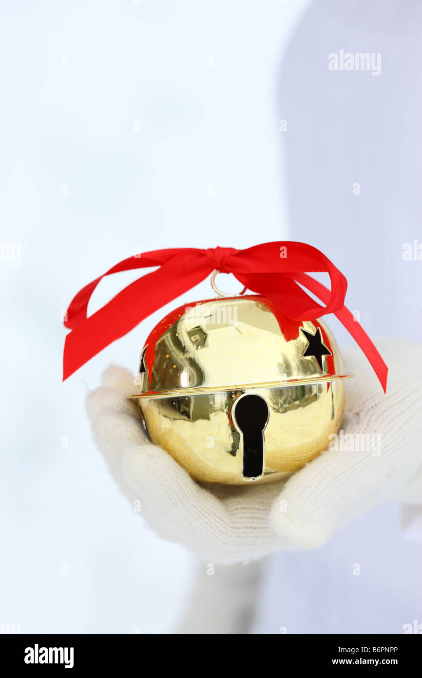 Hände mit Winterhandschuhe holding Christmas jingle Bell mit roter Schleife Stockfoto