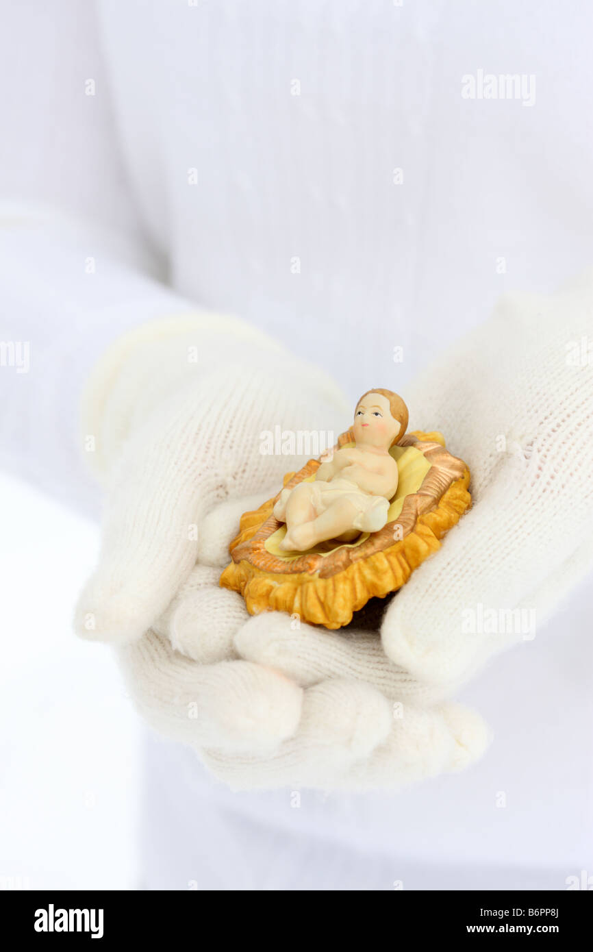 Hände mit Winterhandschuhe halten Baby Jesus Geburt Szene Figur Stockfoto