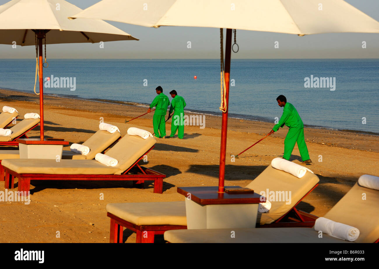 Gastarbeiter aus Südostasien Reinigung des Strandes vor einem Luxushotel, Muscat, Sultanat von Oman Stockfoto