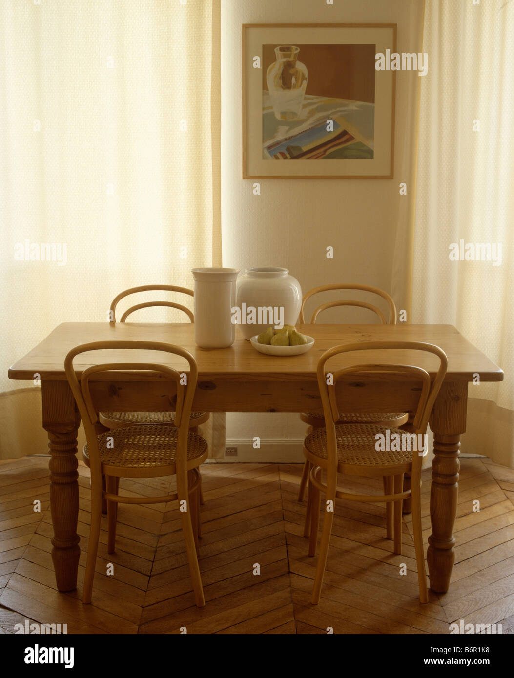 Thonet Bugholzstühle und kleinen hölzernen Tisch im Speisesaal mit Bild an die Wand zwischen den Fenstern mit cremefarbenen Voile Vorhänge Stockfoto