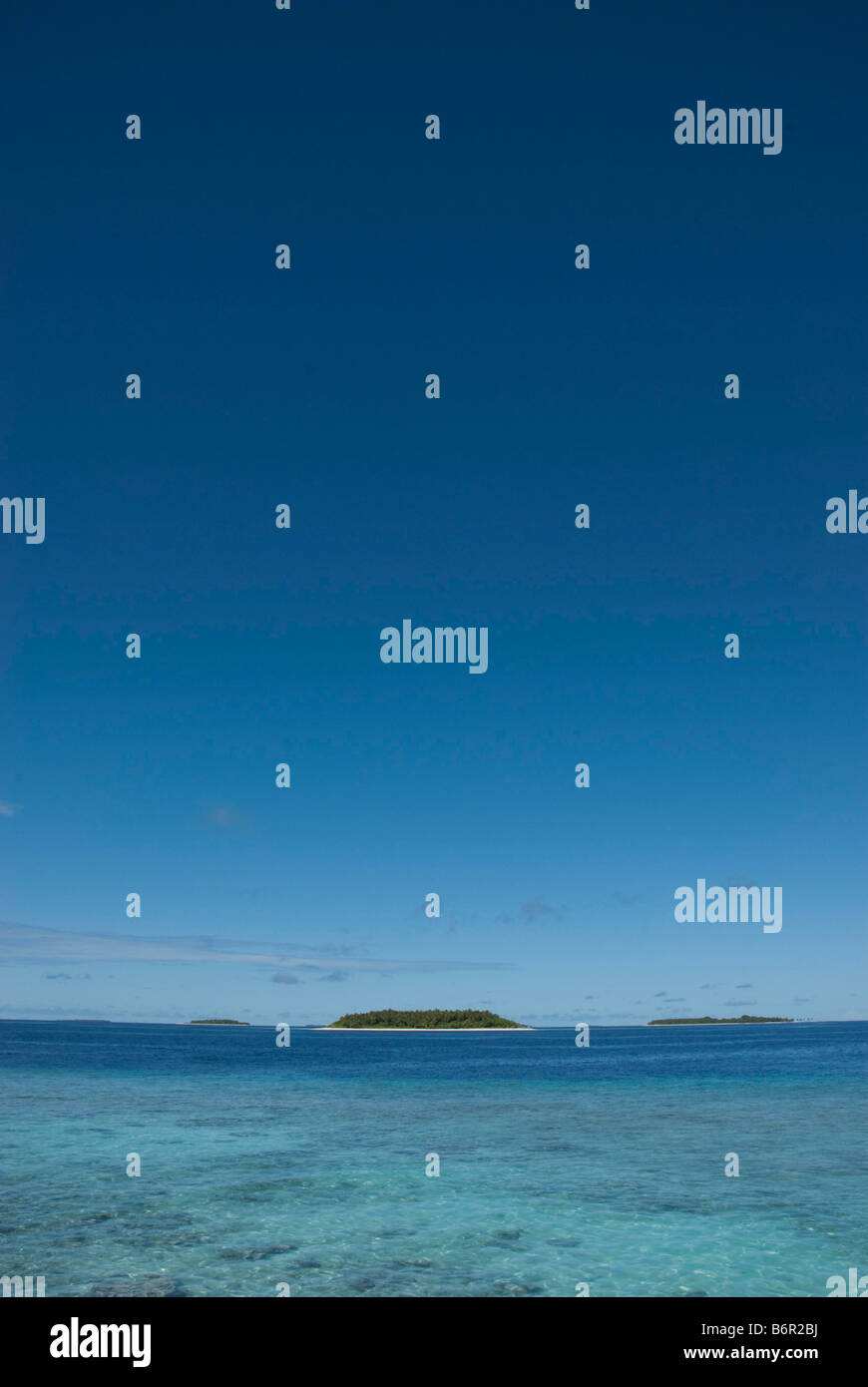 Kleinen tropischen Inseln auf den Malediven und klaren seichten Wasser über Korallenriff in den Vordergrund und tiefblauen Himmel. Stockfoto