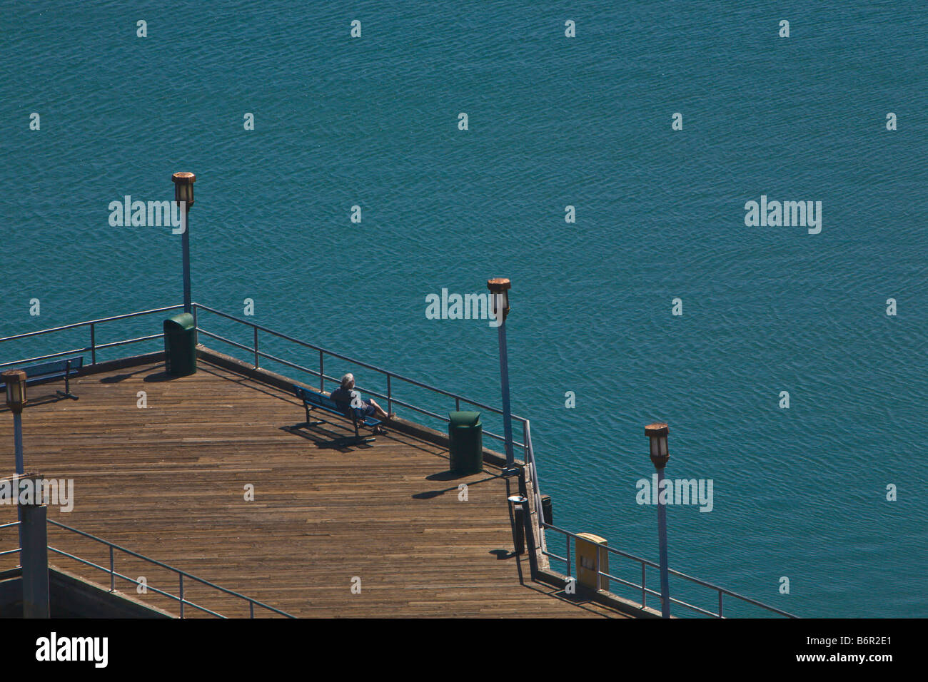 Senior grau dunkelhaarigen Mann sitzen auf Bank auf Pier am Meer starrt Stockfoto