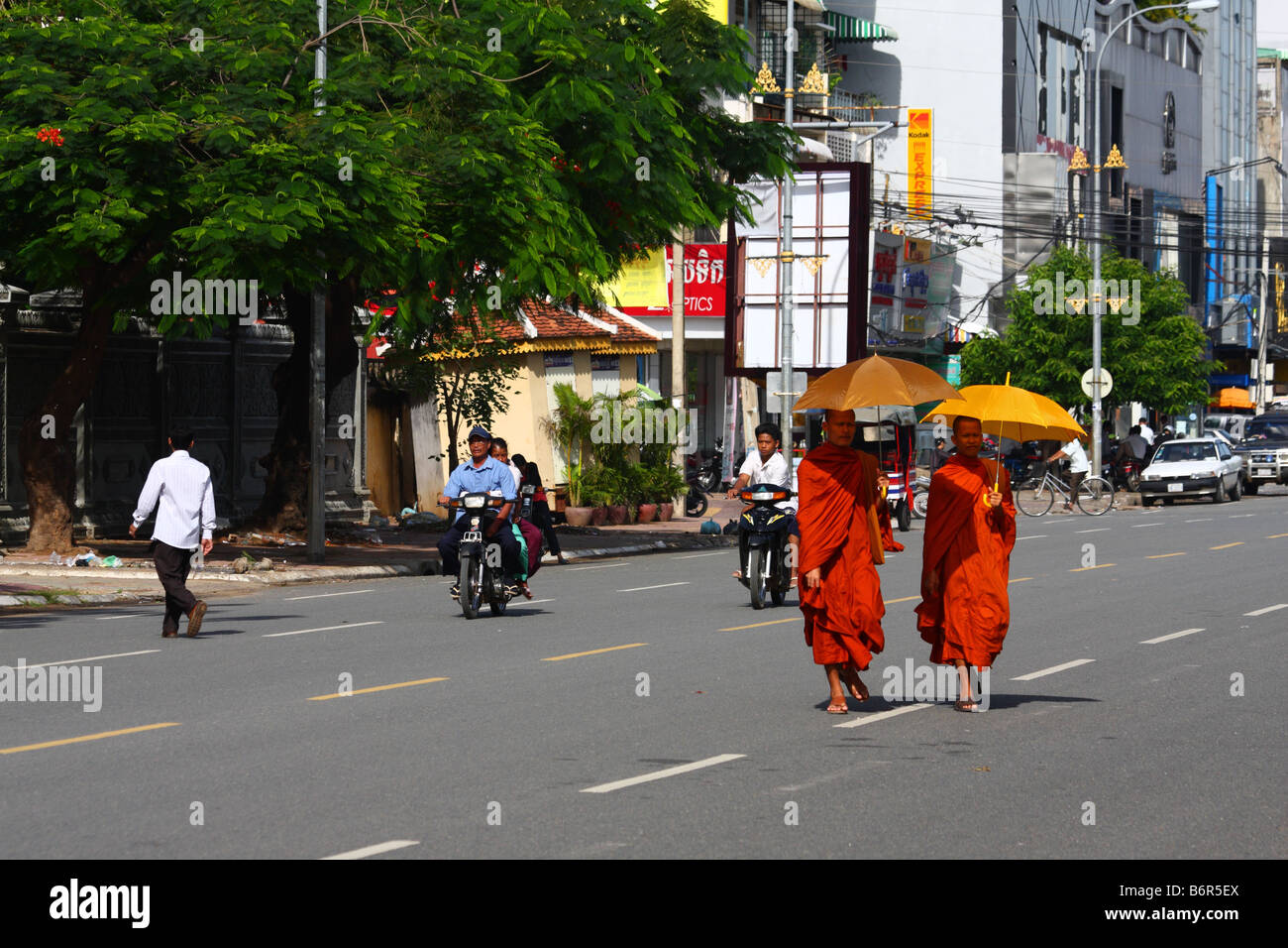 Zwei 2 buddhistische Mönche in Safran Roben zu Fuß mit Sonnenschirmen in den Straßen von Phnom Penh, Kambodscha Stockfoto