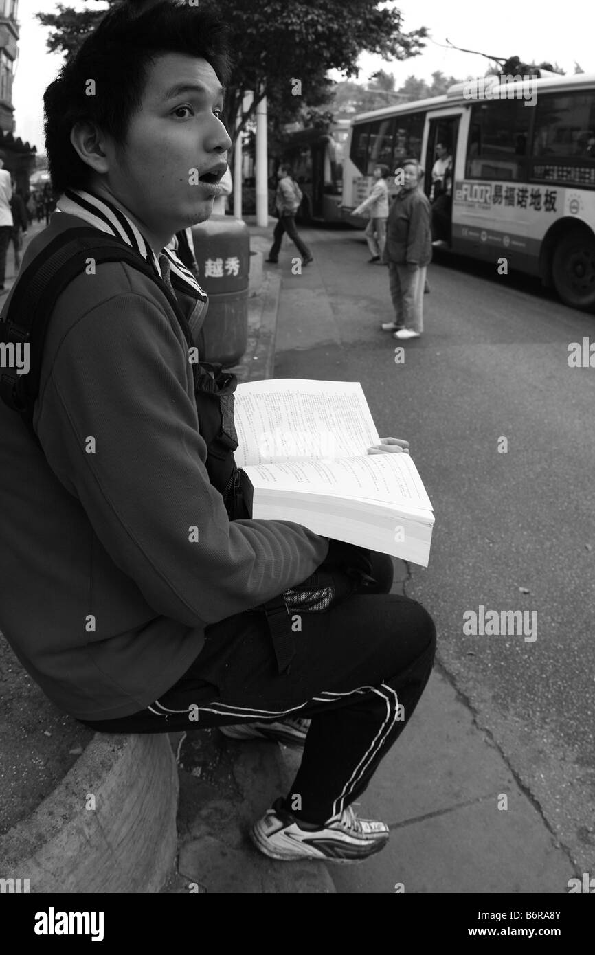 Junge männliche chinesischer Student sitzen Buch überrascht mit Mund öffnen Stockfoto
