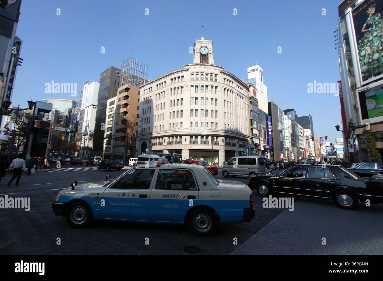 Ein blaues Taxi übergibt die Hattori Clock Tower auf der Wako Department Store in Ginza, Tokio, Japan Stockfoto