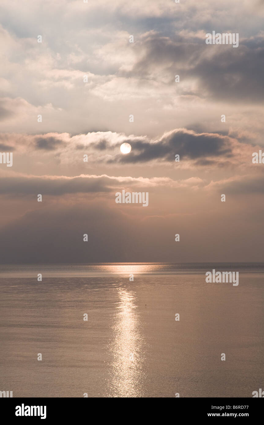 Sonne über dem Meer an einem kalten Nachmittag teilweise verdeckt durch Wolken - wales Cardigan Bay UK Stockfoto