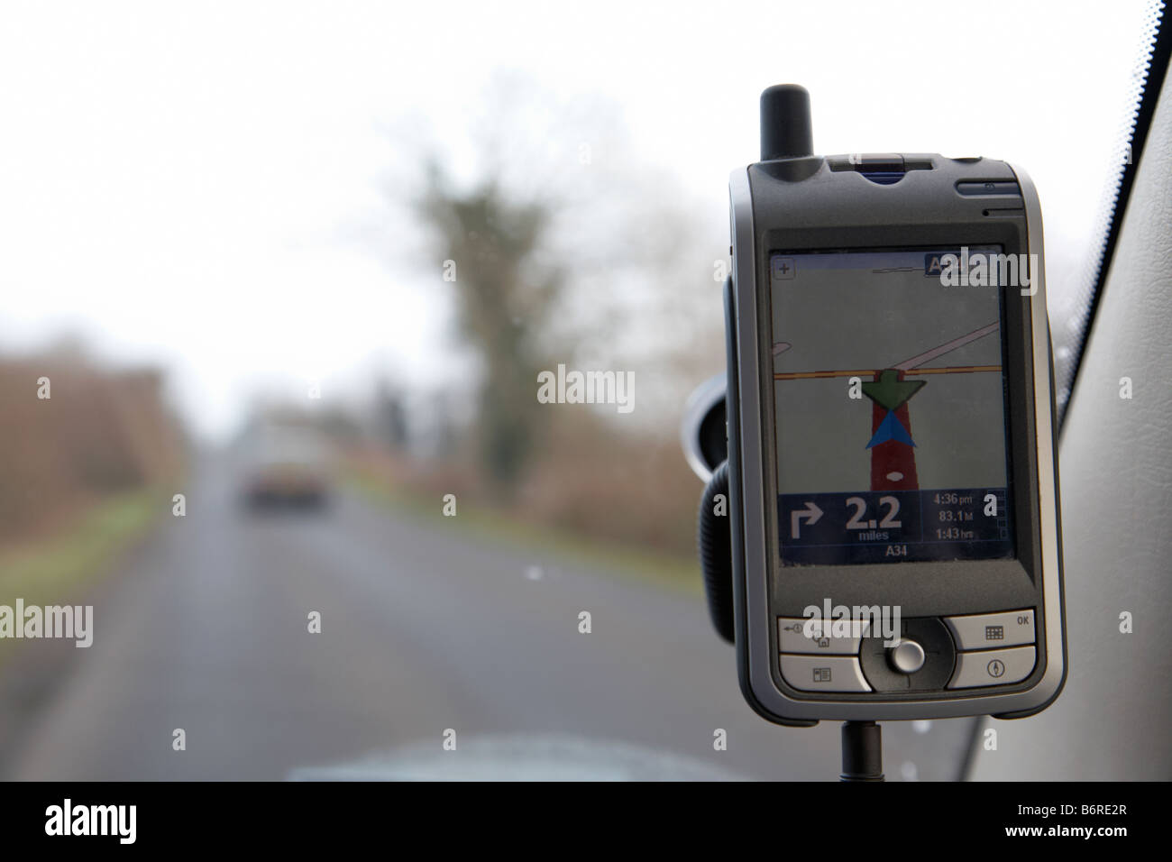 Navi zeigt u-Turn auf einem Pocket-pc angeschlossen an ein Auto Windschutzscheibe auf einer Landstraße Stockfoto