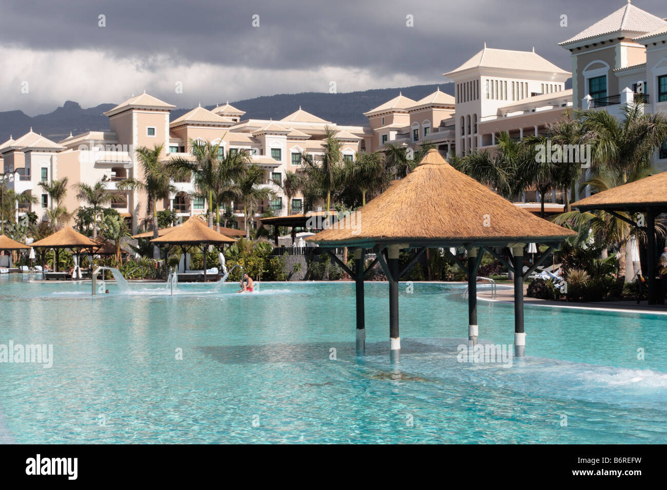 Der Poolbereich des Hotels Sol Melia Gran Palacio de Isora im Sonnenschein während Sturm Wolken über den Bergen erscheinen Stockfoto