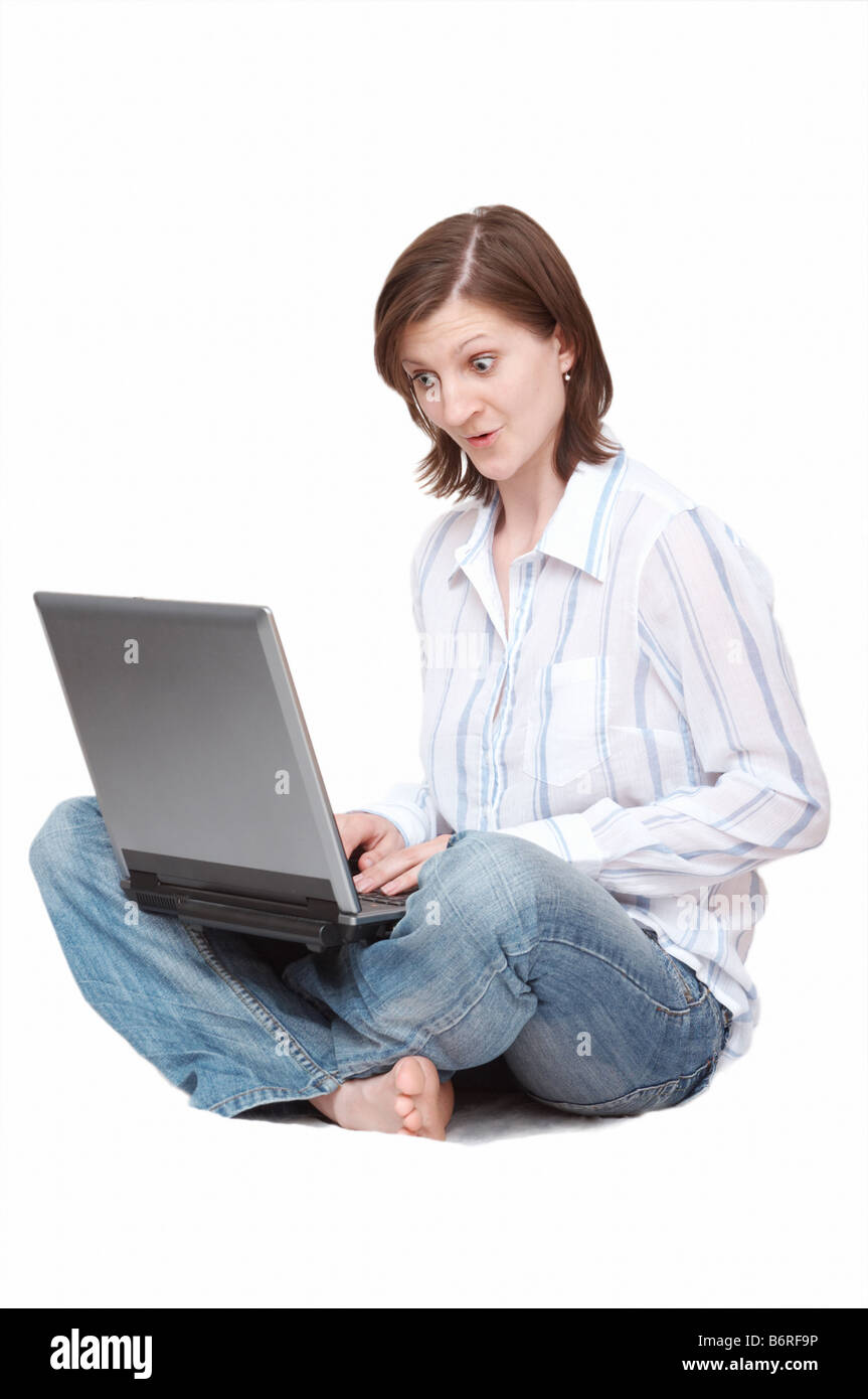 erstaunt Frau mit Notebook auf dem Boden sitzend Stockfoto