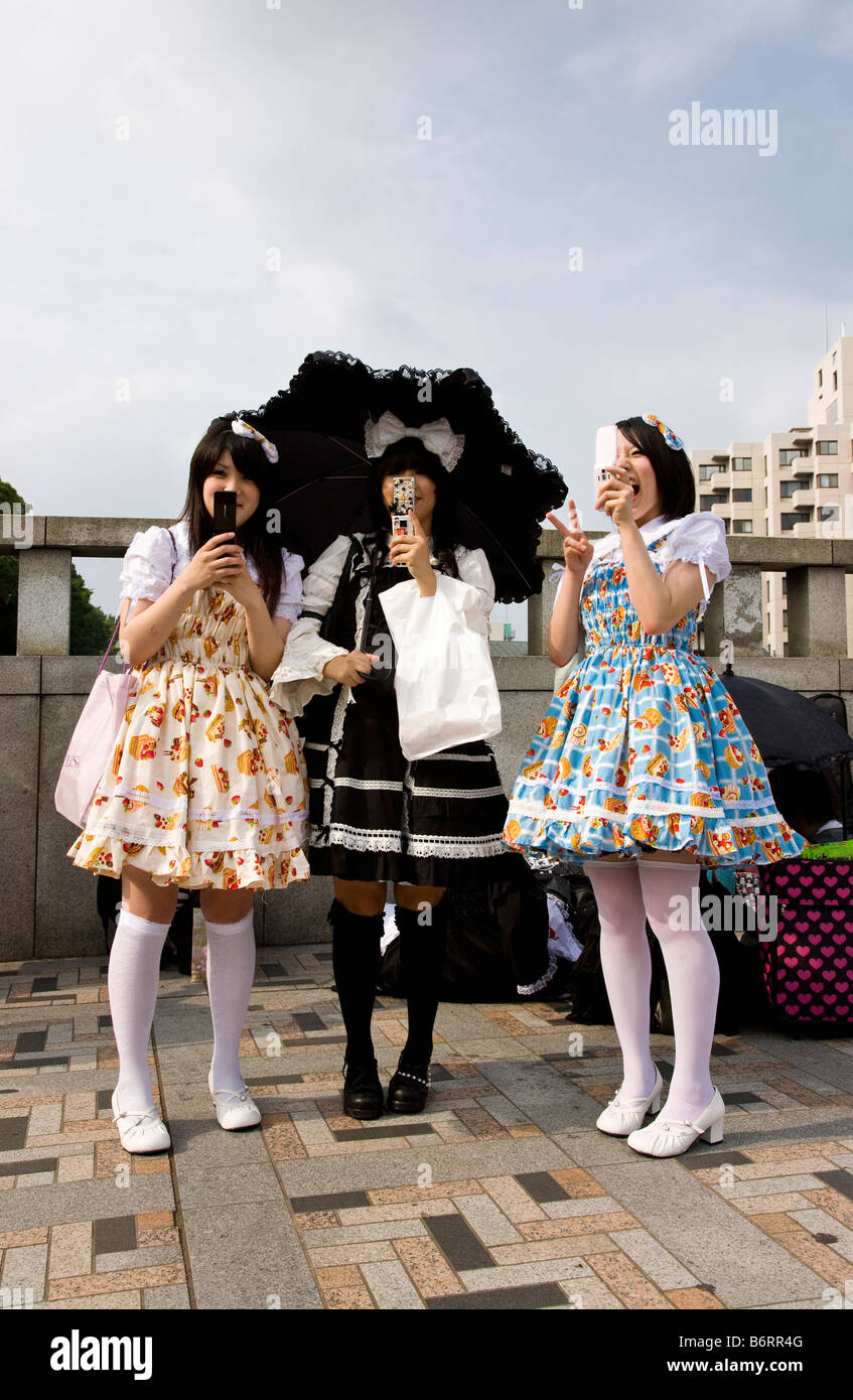 Glücklich japanische Jugendliche verkleidete sich als Puppen in Harajuku, spielen mit ihren Handys Stockfoto