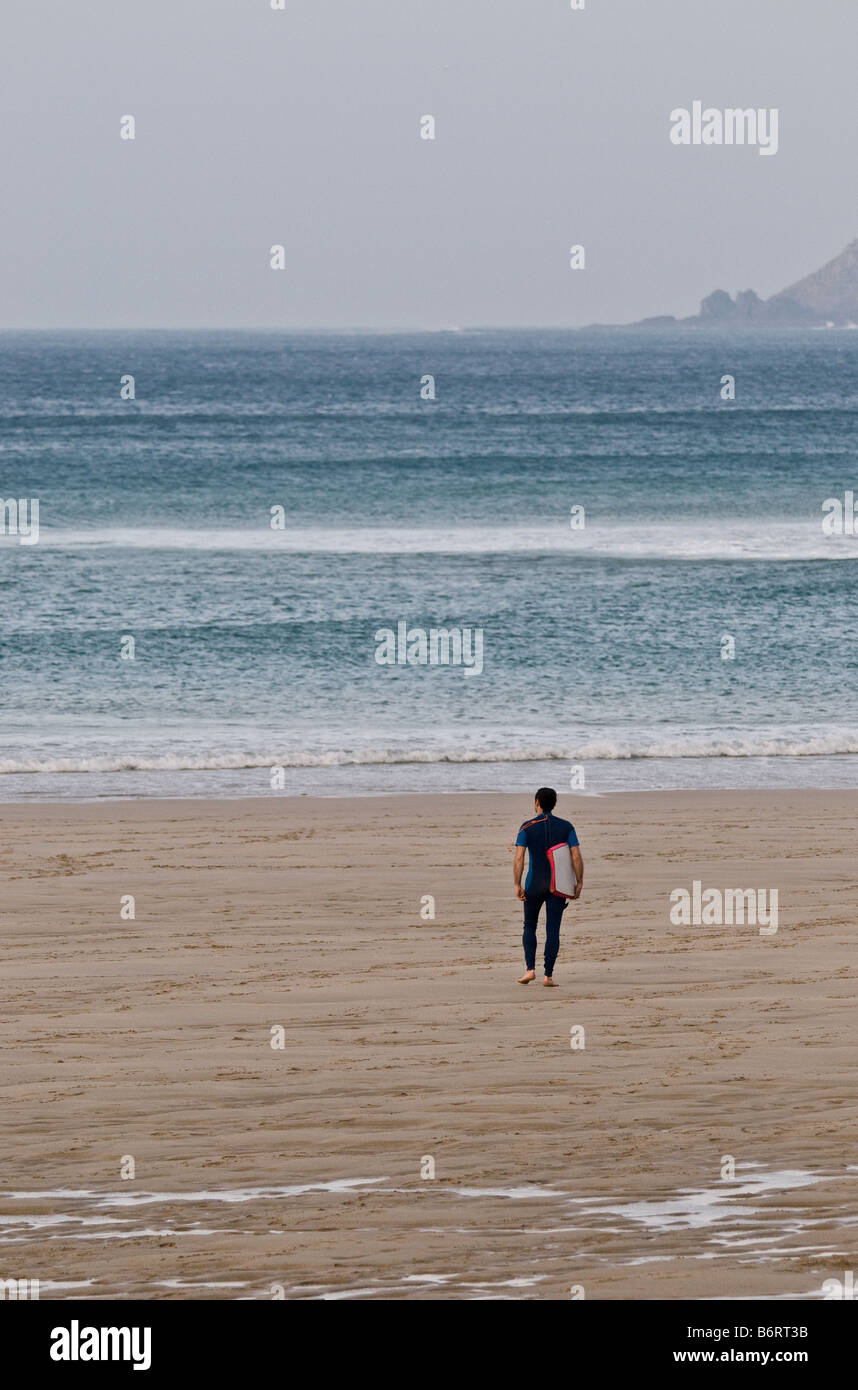 Ein Surfer, zu Fuß in Richtung Meer am Sennen in Cornwall. Stockfoto