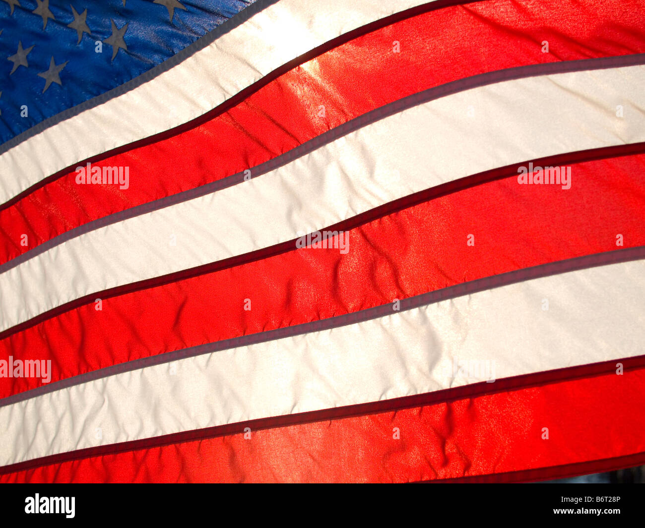 Amerikanische Flagge wehenden Wind wieder beschienen von Sonne Stockfoto