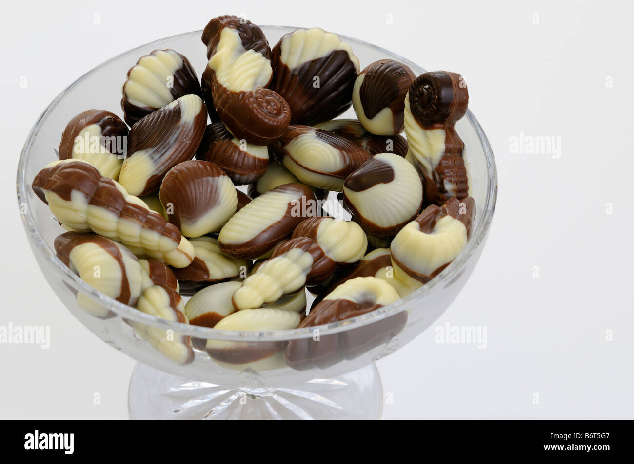 Belgische Muschel geformt schwarz weiß und Milchschokolade in eine Kristallschale auf weißem Hintergrund Stockfoto