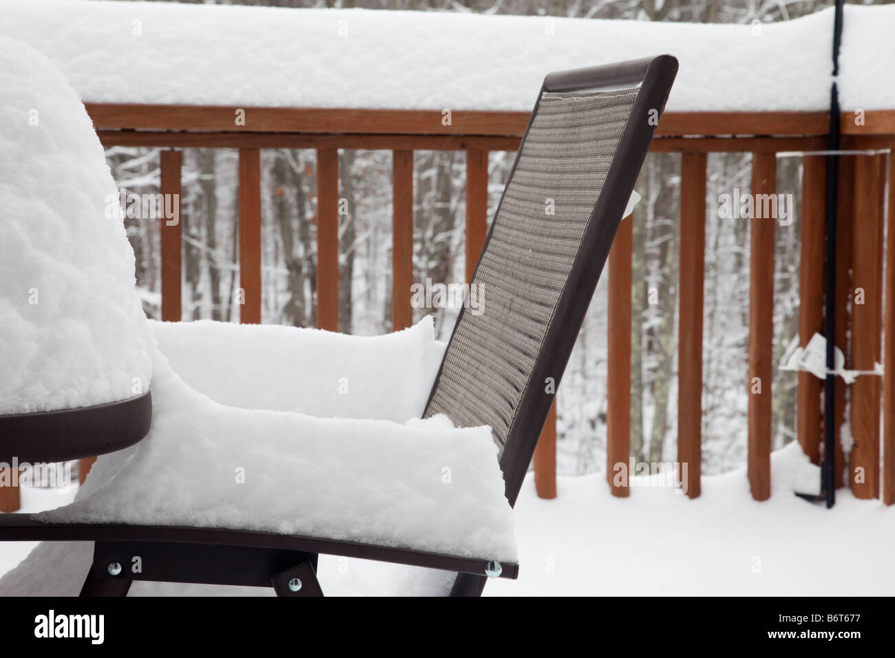 Patiostuhl unter starkem Schneefall auf der Holzterrasse im winter Stockfoto