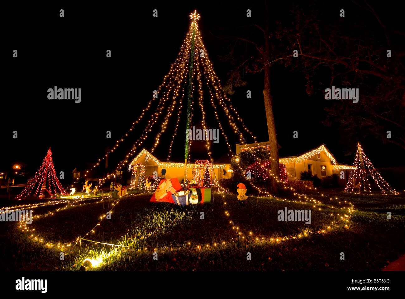 Weihnachten Dekoration Weihnachten Bäume Elfen Zuhause bedeckt in Weihnachten Lichter aufwendige Hof Display dunkel Stockfoto