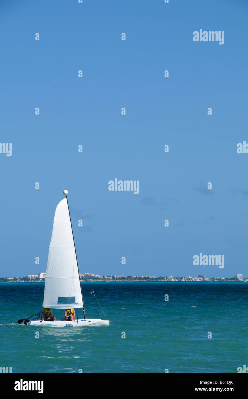 Hobie Cat Catamaran Segeln Playa Mujeres Mexiko // PLAYA MUJERES, Mexiko - Touristen segeln einen Hobie Cat Katamaran vor dem Strand in Playa Mujeres in Mexiko. Playa Mujeres liegt an der Nordküste der Halbinsel Yucatan, etwa 10 Kilometer nördlich von Cancun. Der Strand ist Teil des Entwicklungsgebiets Costa Mujeres, das zu einem beliebten Ziel für Urlaubstourismus und Wassersportaktivitäten geworden ist. Hobie Cat Katamarane werden aufgrund ihrer Stabilität und Bedienfreundlichkeit häufig für Freizeitsegel in Strandresorts in der Karibik und im Golf von Mexiko verwendet Stockfoto