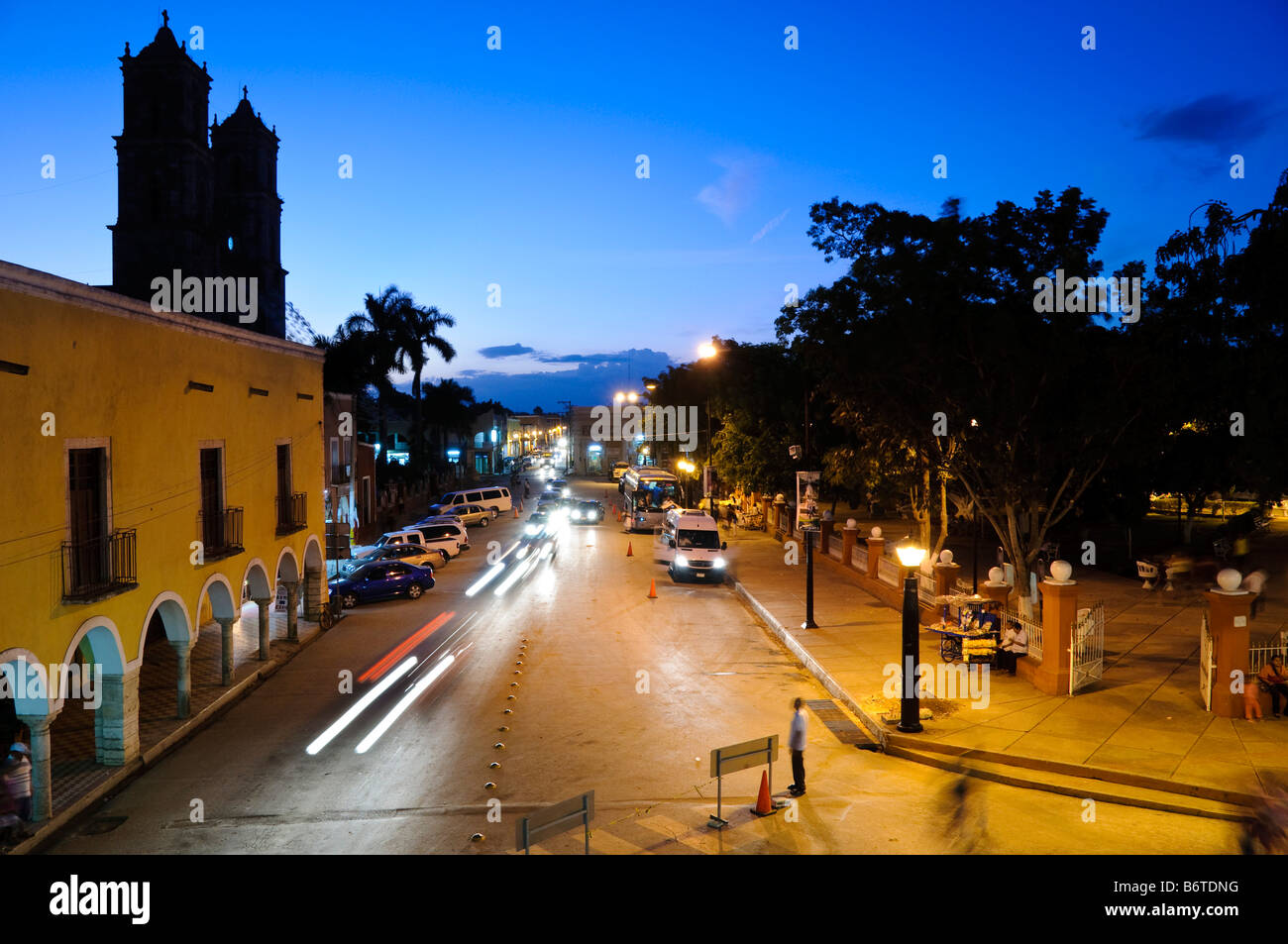 Valladolid Downtown Night Street Scene Yucatan Mexico // VALLADOLID, Yucatan, Mexiko – Eine nächtliche Straßenszene in der Innenstadt von Valladolid, aufgenommen vom Balkon des Rathauses. Die Aussicht zeigt die koloniale Architektur und die lebhafte Atmosphäre dieser historischen Stadt Yucatecan. Beleuchtet von Straßenlaternen, zeigt die Szene das lokale Leben und den Charme von Valladolids zentraler Gegend mit seinen farbenfrohen Gebäuden, Fußgängern und der Mischung aus traditioneller und moderner mexikanischer Kultur. Stockfoto