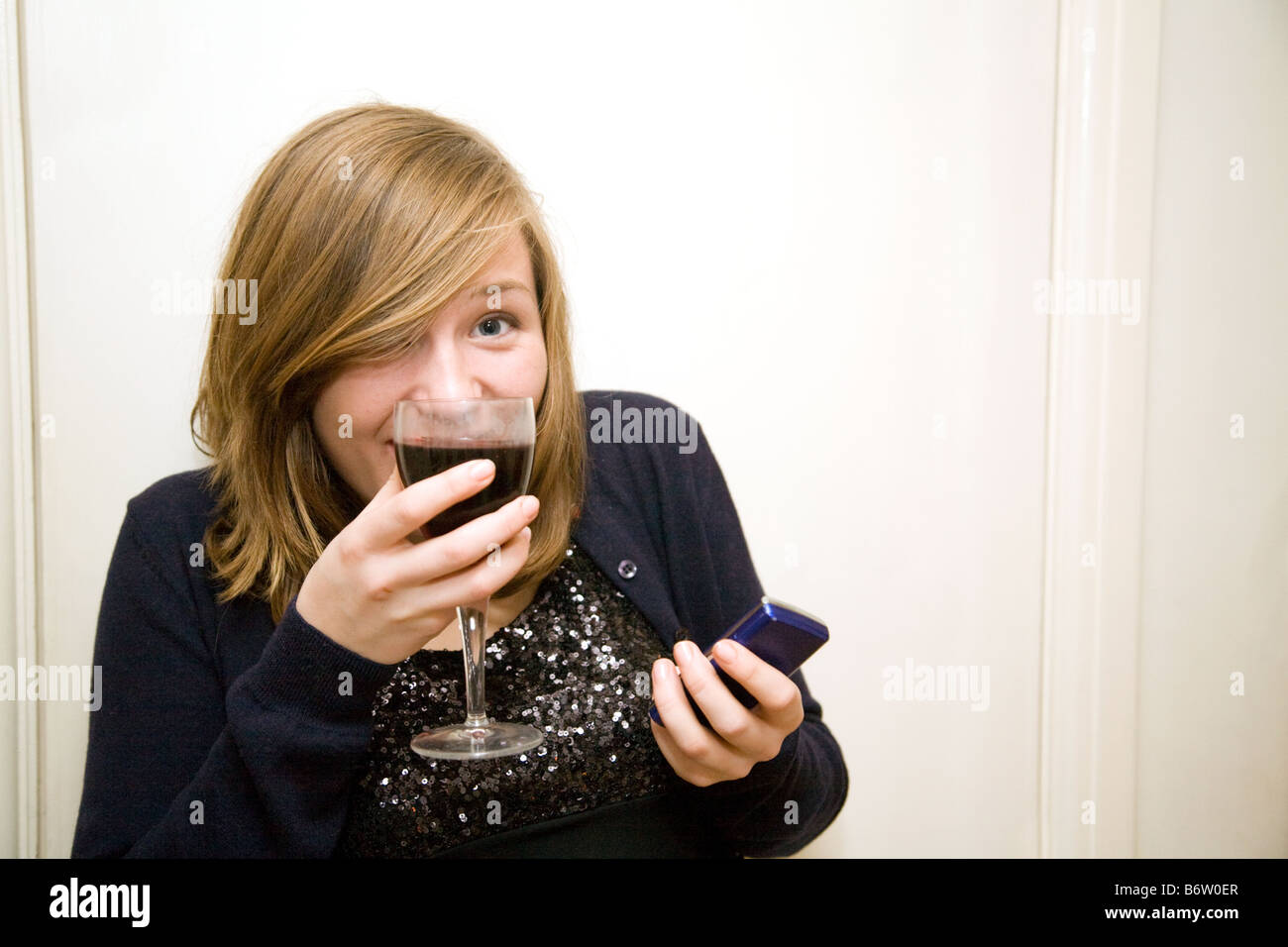 Blonde Teenager-Alter im Alter von 14-15 Jahre alt, trinken Wein und SMS mit ihrem Handy, UK Stockfoto