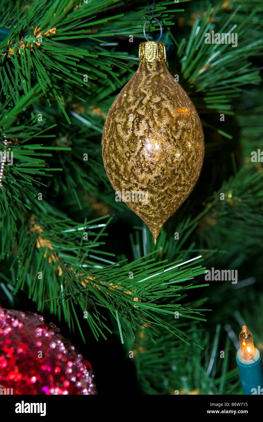 Nahaufnahme von gold farbigen dekorativen Glas Christbaumkugel am Weihnachtsbaum mit Teil einer roten Kugel und Licht im Vordergrund Stockfoto