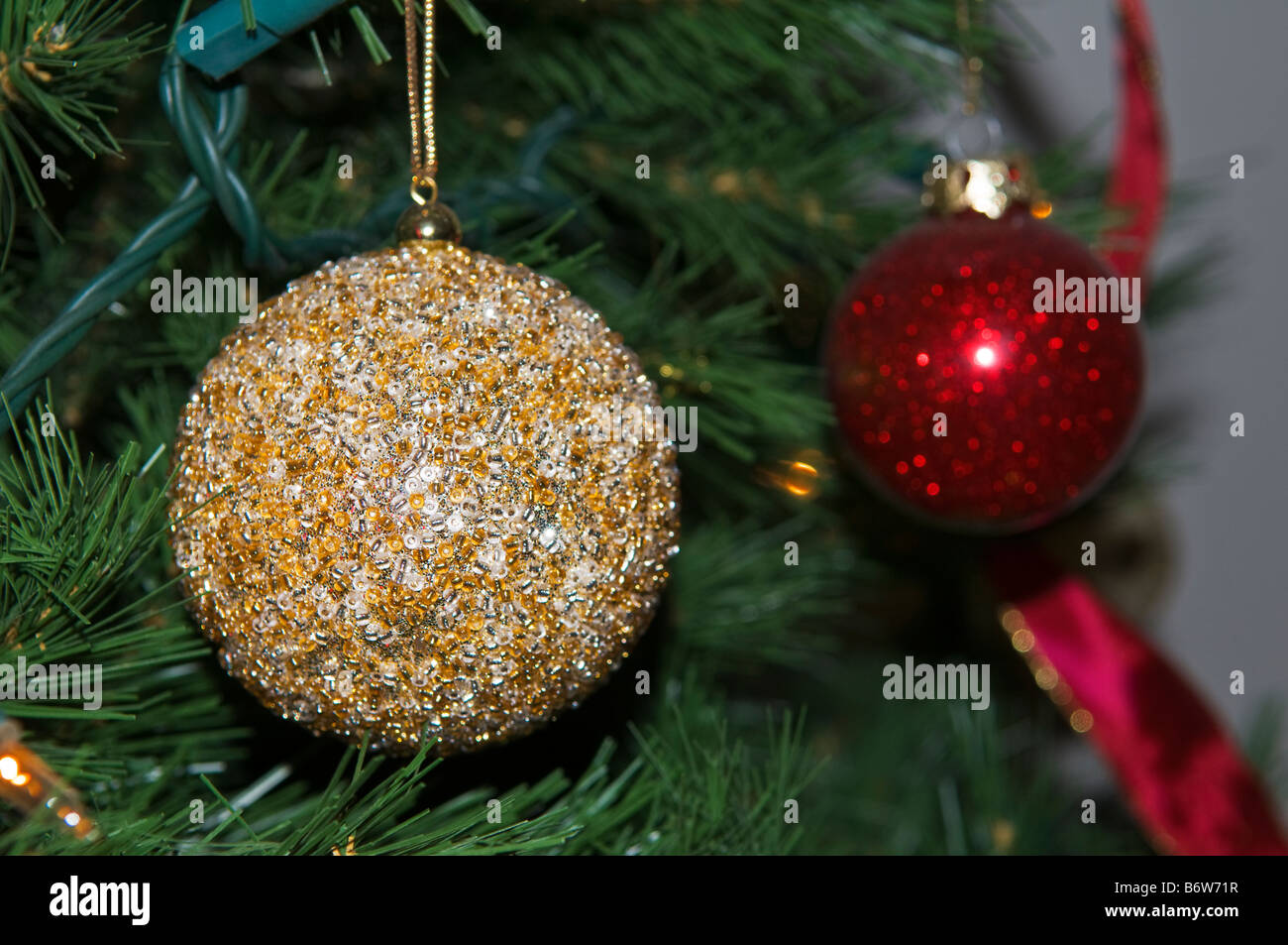Nahaufnahme von gold farbigen dekorative Spielerei am Weihnachtsbaum mit roten Tand und rote Schleife im Hintergrund Stockfoto