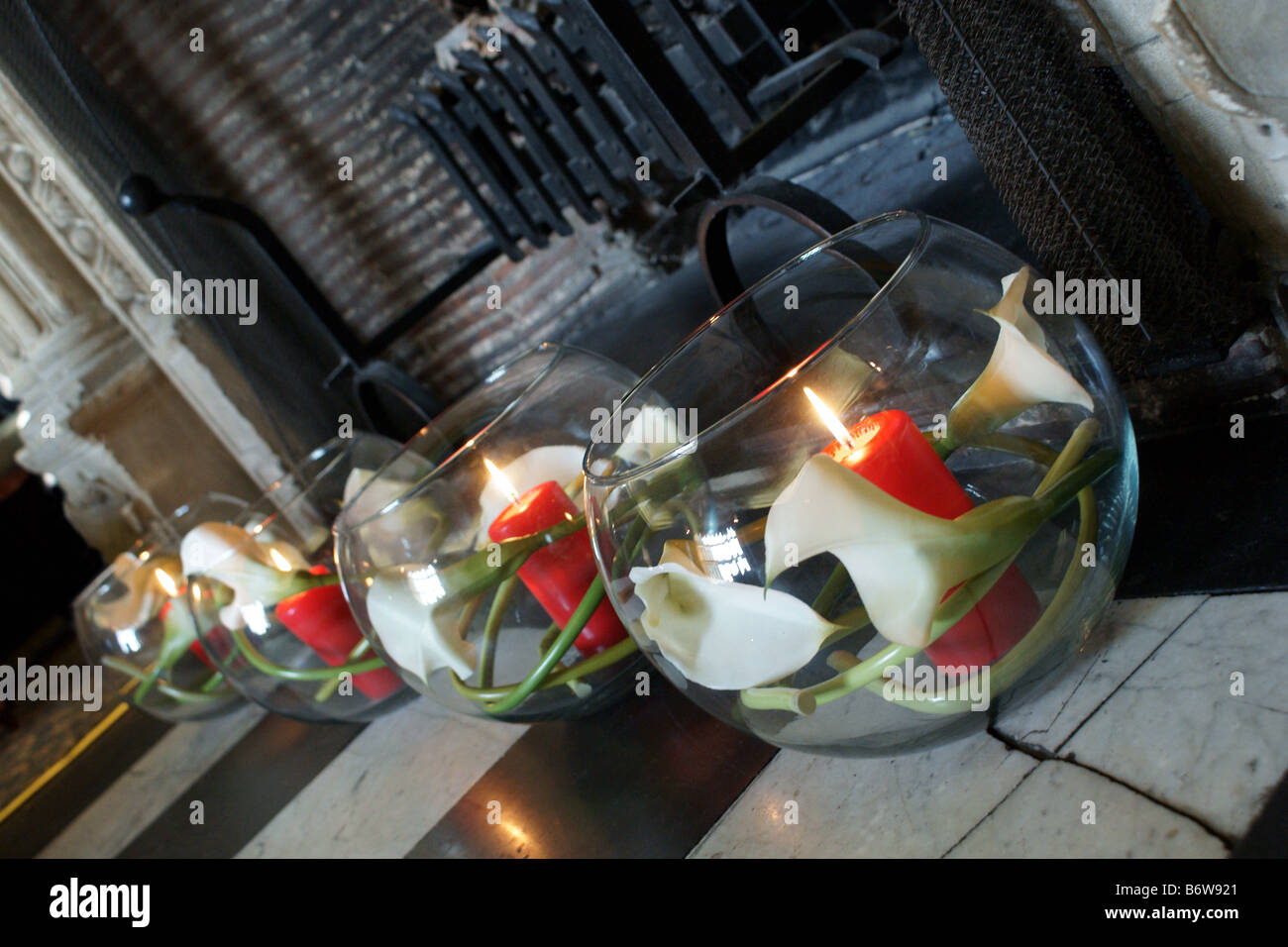 Goldfischglas Vasen mit Kerzen im Inneren in alten Kamin Stockfoto
