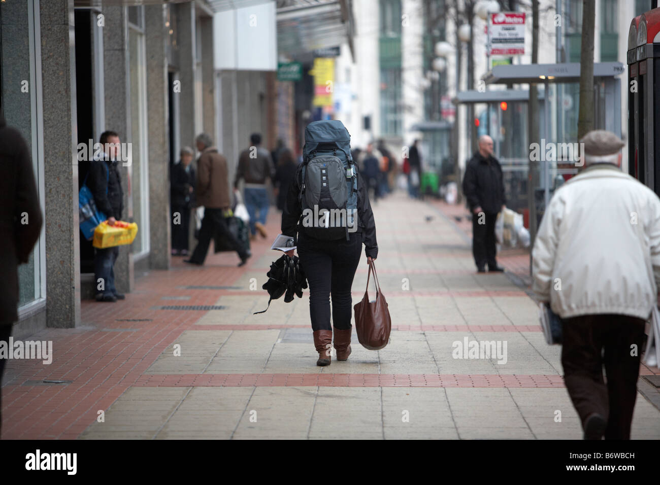 einsame weibliche Rucksack Reisenden entlang Stadtstraße mit schweren Gepäck Belfast Nordirland Stockfoto