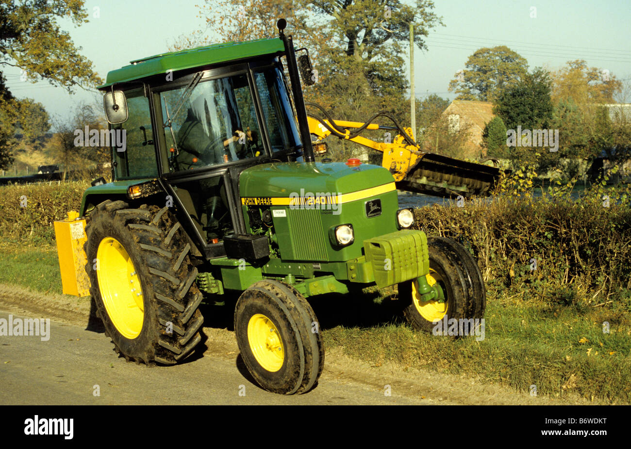 Landwirt dreschenden Weißdorn Hecke / John Deere 2140 Schlepper, Wiltshire, Großbritannien. Stockfoto