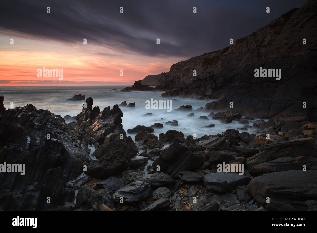 Wilde Küste bei Sonnenuntergang mit Wellenbewegungen im Naturpark Sintra, Portugal Stockfoto