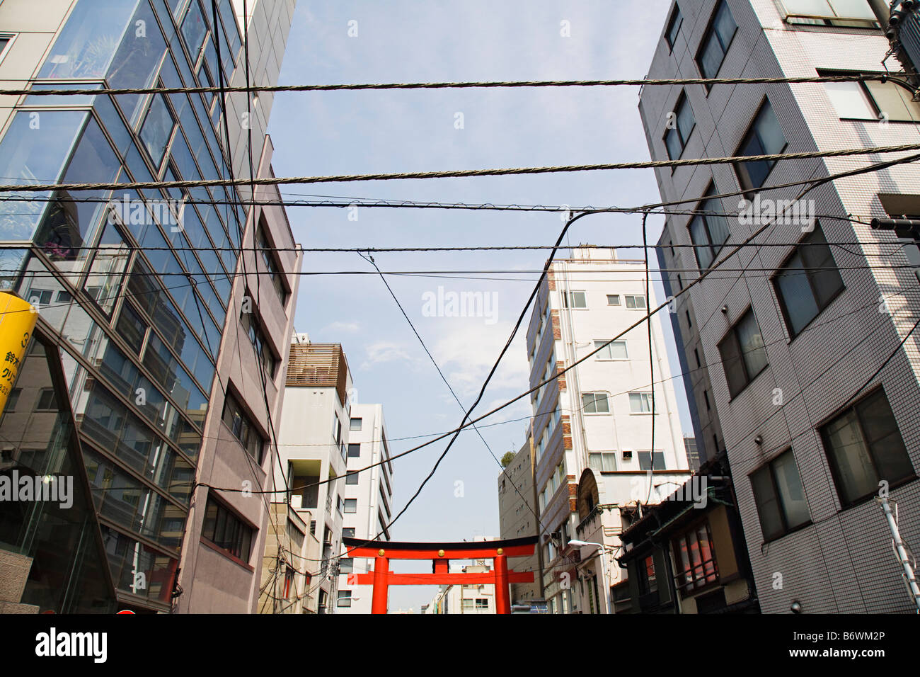 Elektrische Leitungen und Torii-Tor zwischen Hochhäusern Stockfoto