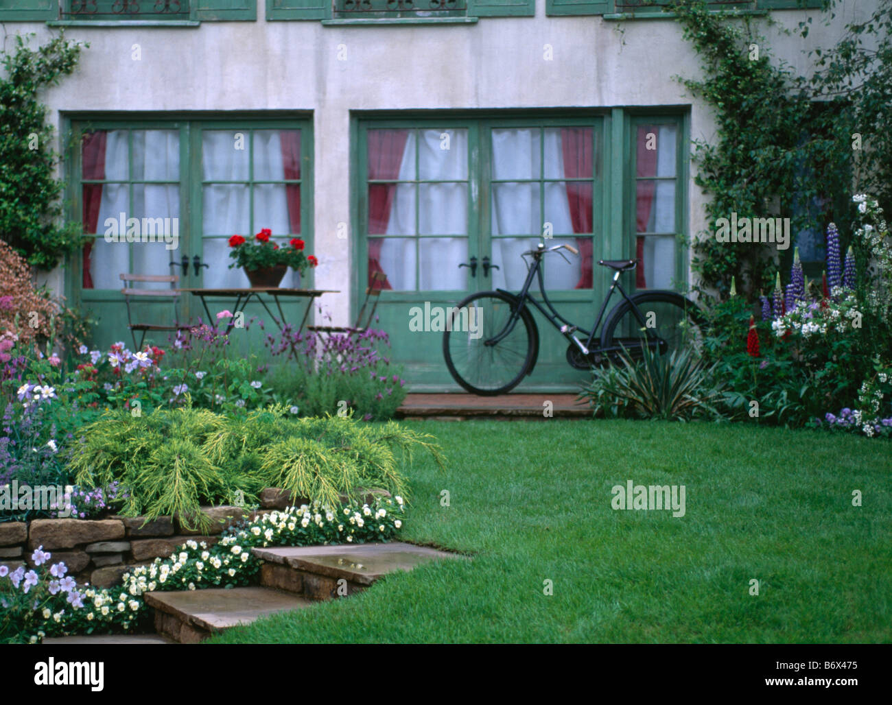 Wiese vor Haus mit alten altmodischen Fahrrad gelehnt grünen Flügeltüren Stockfoto
