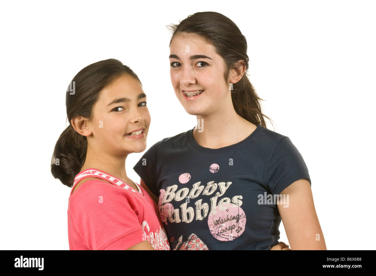 Ein Porträt von 2 Mädchen (11 und 14) Schwestern und Freundinnen vor einem Hintergrund von reinem weiß (255). Stockfoto