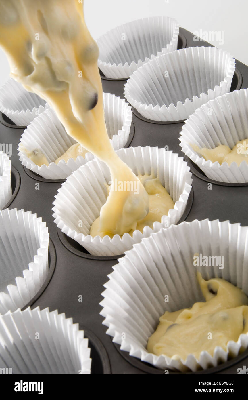 Dollopping Kuchen mix in kleinen Kuchen Fällen chocolate Chip Muffins machen. Einen großen Esslöffel ist genug für jeden Kuchen. Stockfoto