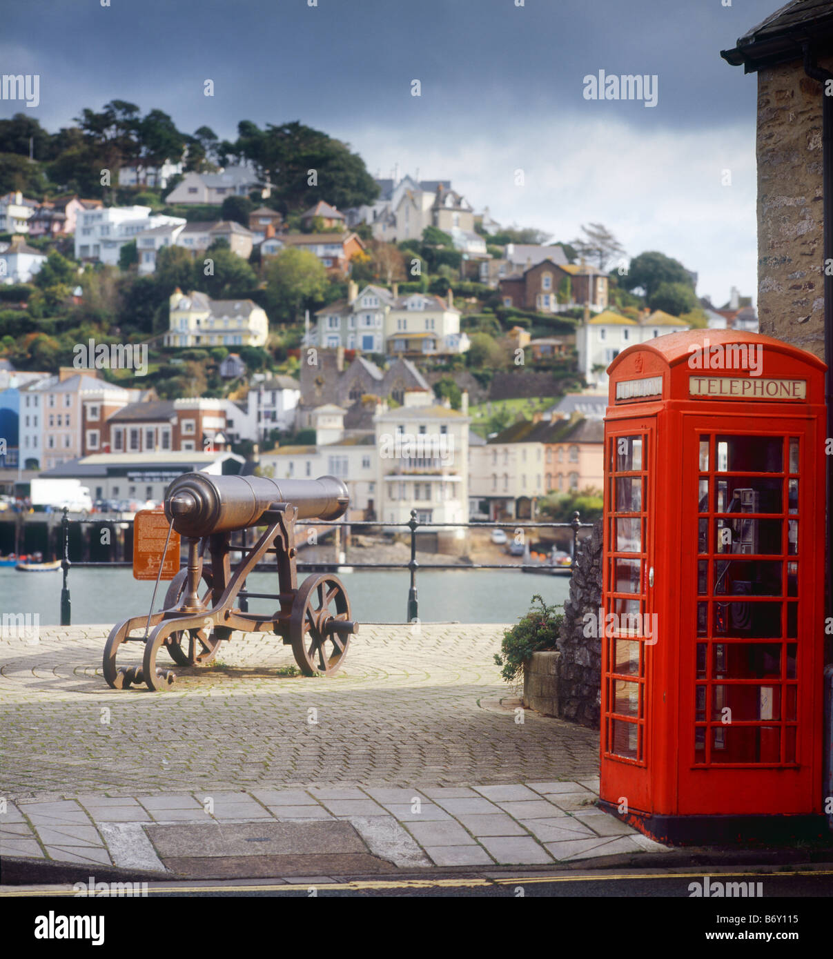 Kanone und ein öffentliches Telefon am Kai in Dartmouth, Devon, mit Kingwear im Hintergrund jmh Stockfoto