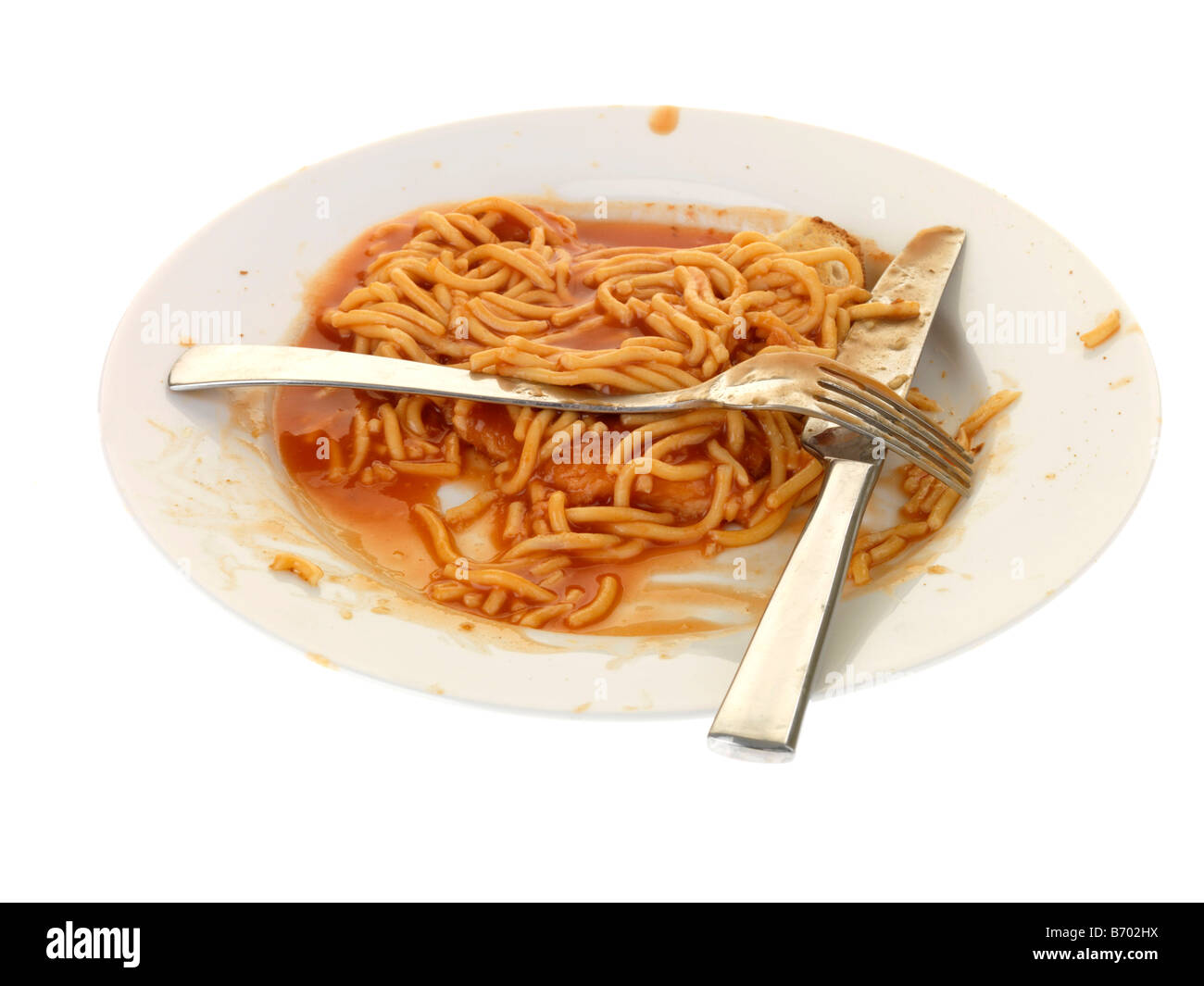 Aus der Dose Spaghetti in Tomatensoße auf Toast Reste auf einem Teller mit Messer und Gabel Isoliert gegen einen weißen Hintergrund mit Keine Personen Stockfotografie