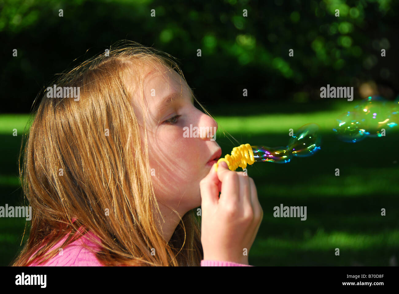 Junges Mädchen bläst Seifenblasen in einem park Stockfoto