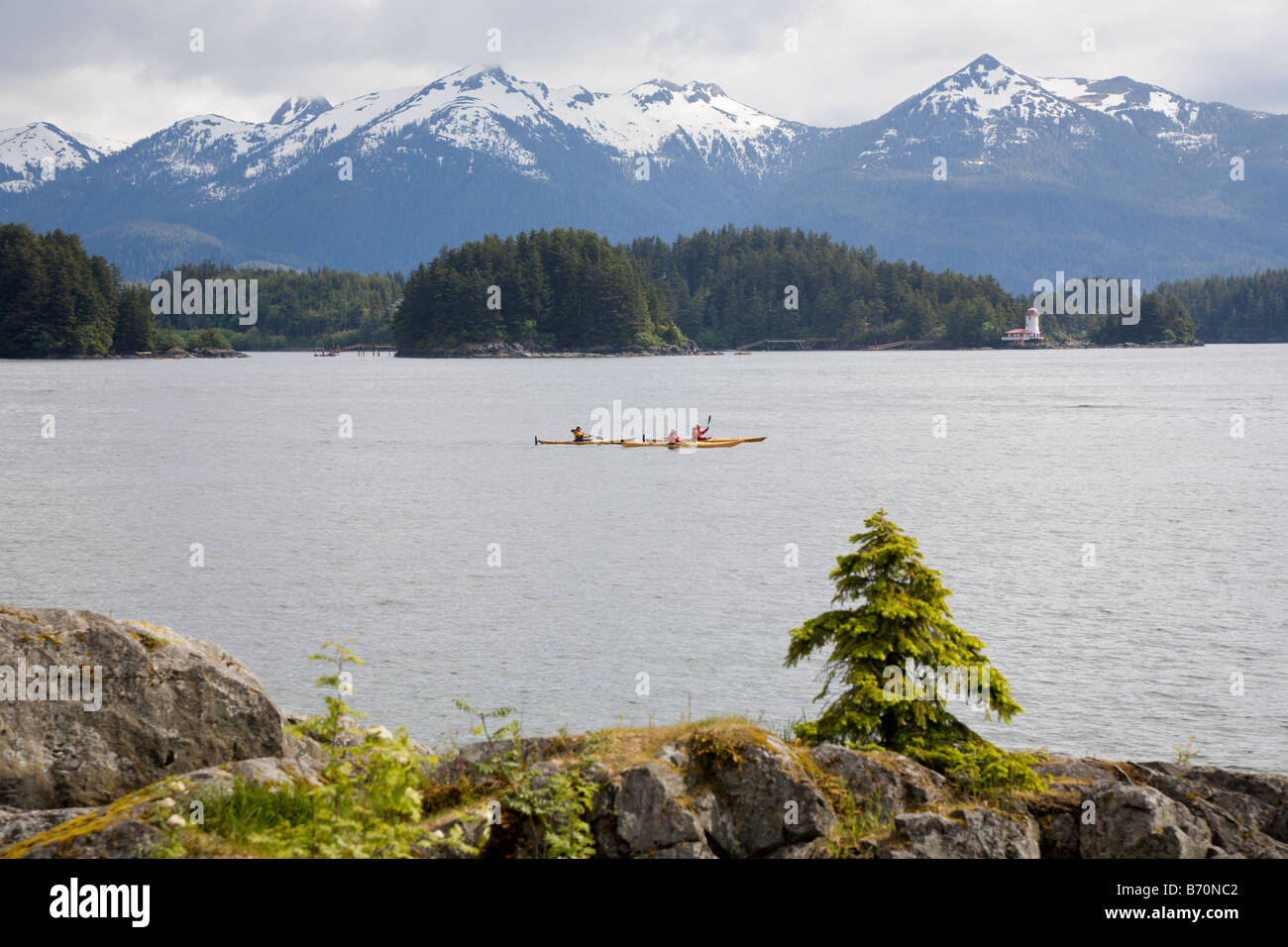 Kajakfahrer pass vor schneebedeckten Bergen und Leuchtturm im östlichen Ärmelkanal der Inside Passage in Sitka, Alaska Stockfoto