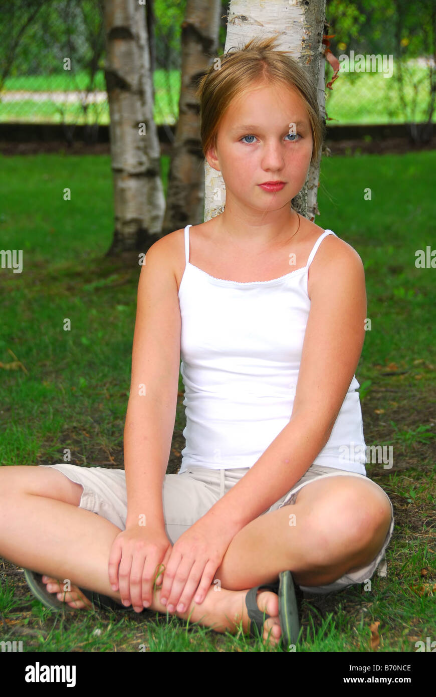 Porträt von einem jungen hübschen Mädchen sitzen unter einer Birke in einem park Stockfoto